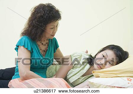 Stock Photo - Senior woman consoling her daughter on the bed. Fotosearch