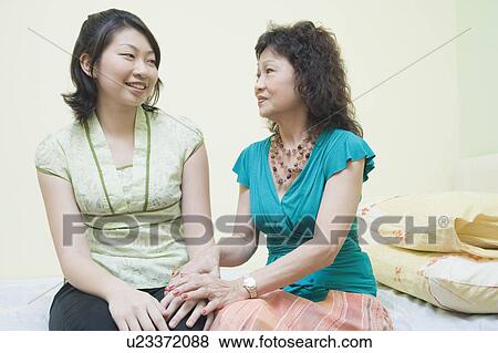 Stock Photo - Senior woman consoling her daughter on the bed. Fotosearch