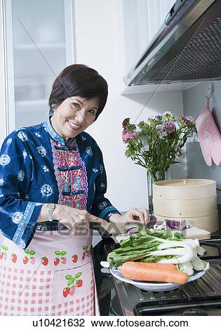 Senior woman cutting vegetables and smiling in a kitchen View Large Photo Image Stock Image - Senior woman cutting vegetables and smiling in a kitchen. Fotosearch