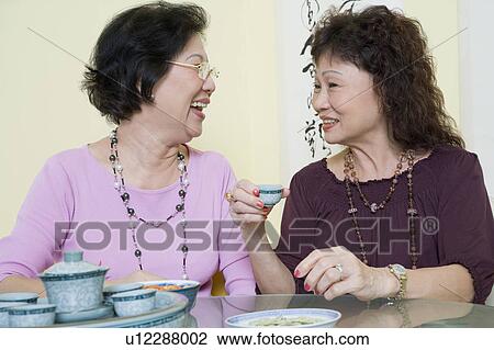 Two senior women sitting at a table and looking at each other View Large Photo Image Stock Image - Two senior women sitting at a table and looking at each other. Fotosearch