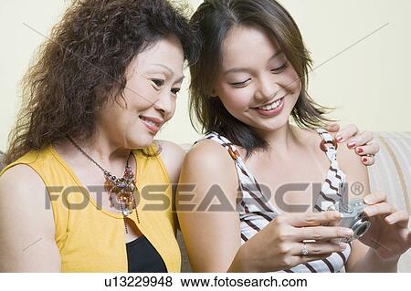 Stock Photo - Close-up of a senior woman sitting with her granddaughter and looking photographs in a digital camera. Fotosearch