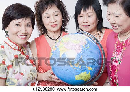 Stock Image - Close-up of three senior women and a mature woman holding a globe. Fotosearch