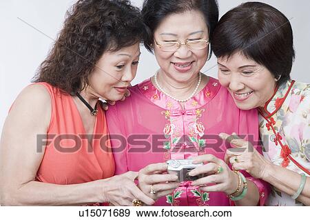 Stock Photo - Close-up of three senior women looking at a digital camera and smiling. Fotosearch