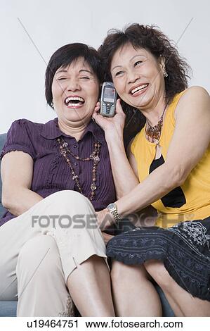 Close-up of two senior women talking on a mobile phone and smiling View Large Photo Image Stock Image - Close-up of two senior women talking on a mobile phone and smiling. Fotosearch