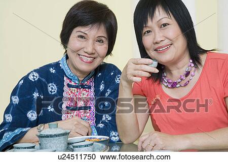 Stock Image - Portrait of a mature woman and a senior woman sitting at a table. Fotosearch