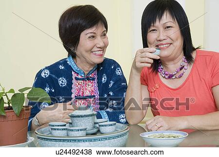 Portrait of a mature woman holding a tea cup and smiling with a senior woman sitting beside her View Large Photo Image Stock Photo - Portrait of a mature woman holding a tea cup and smiling with a senior woman sitting beside her. Fotosearch