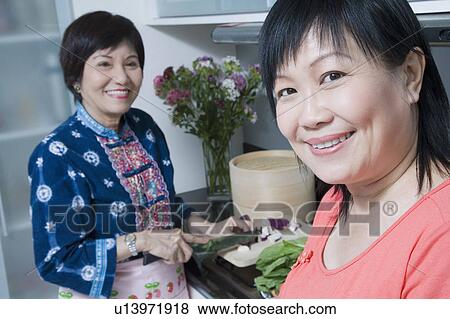 Portrait of a mature woman smiling with her mother cutting vegetables in a kitchen View Large Photo Image Stock Photo - Portrait of a mature woman smiling with her mother cutting vegetables in a kitchen. Fotosearch
