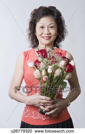 Portrait of a senior woman holding a bouquet of flowers View Large Photo Image Stock Image - Portrait of a senior woman holding a bouquet of flowers. Fotosearch