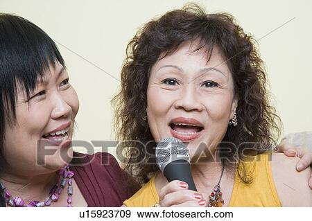 Stock Photo - Portrait of a senior woman singing with a mature woman in front of a microphone. Fotosearch