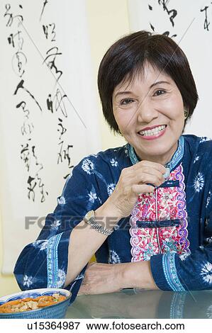 Stock Photo - Portrait of a senior woman sitting at a table and smiling. Fotosearch