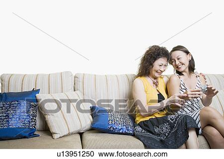 Stock Image - Senior woman and her granddaughter looking photographs in a digital camera and smiling. Fotosearch