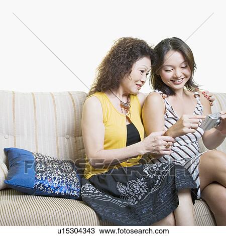 Stock Image - Senior woman and her granddaughter looking photographs in a digital camera and smiling. Fotosearch