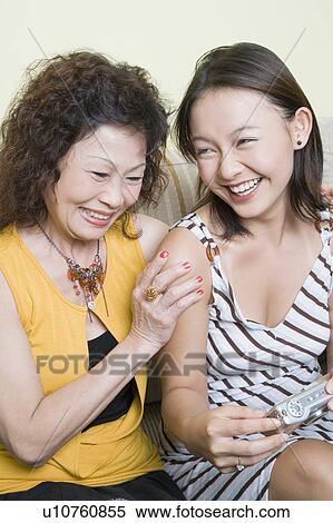 Senior woman and her granddaughter looking photographs in a digital camera and smiling View Large Photo Image Stock Photography - Senior woman and her granddaughter looking photographs in a digital camera and smiling. Fotosearch