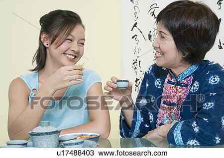 Senior woman sitting with her granddaughter at a table and holding tea cups View Large Photo Image Stock Image - Senior woman sitting with her granddaughter at a table and holding tea cups. Fotosearch