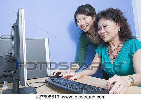 Side profile of a senior woman using a computer with her daughter standing beside her View Large Photo Image Stock Photo - Side profile of a senior woman using a computer with her daughter standing beside her. Fotosearch