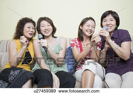 Two young women singing with their grandmothers into microphones View Large Photo Image Stock Photo - Two young women singing with their grandmothers into microphones. Fotosearch