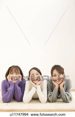 Picture - Three young women lying on floor. Fotosearch