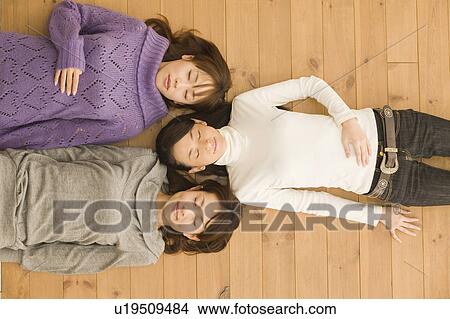 Three young women lying on floor View Large Photo Image Picture - Three young women lying on floor. Fotosearch