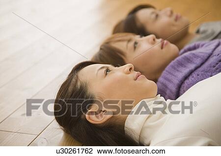 Stock Image - Three young women lying on floor. Fotosearch