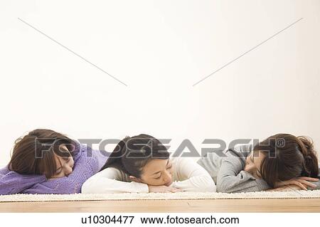 Three young women lying on floor View Large Photo Image Stock Photo - Three young women lying on floor. Fotosearch