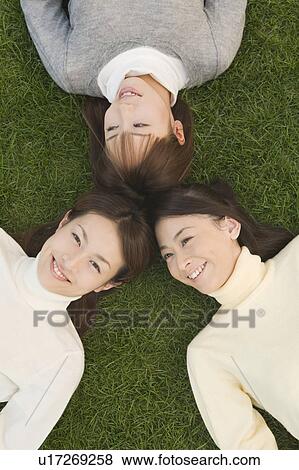 Three young women lying on lawn View Large Photo Image Stock Photo - Three young women lying on lawn. Fotosearch