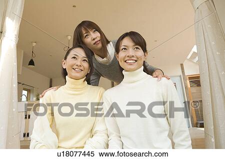 Stock Photography - Three young women sitting at living room. Fotosearch