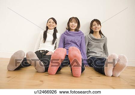 Stock Photograph - Three young women sitting on floor. Fotosearch