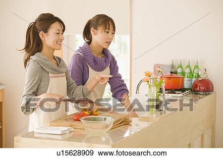 Two young women cooking in kitchen View Large Photo Image Stock Photo - Two young women cooking in kitchen . Fotosearch