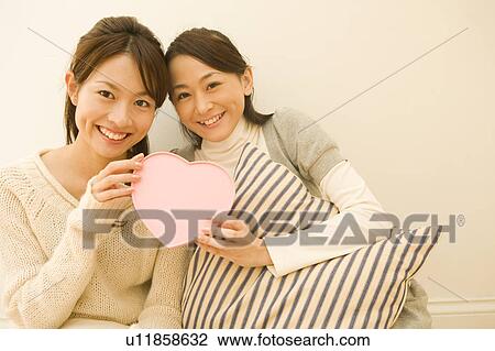 Stock Image - Two young women holding heart box. Fotosearch