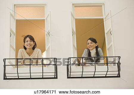 Two young women looking outside from windows View Large Photo Image Stock Image - Two young women looking outside from windows. Fotosearch