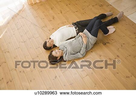 Two young women lying on floor View Large Photo Image Stock Image - Two young women lying on floor. Fotosearch