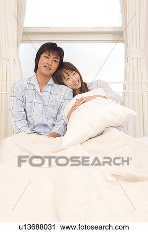 Young couple sitting on bed View Large Photo Image Stock Image - Young couple sitting on bed. Fotosearch