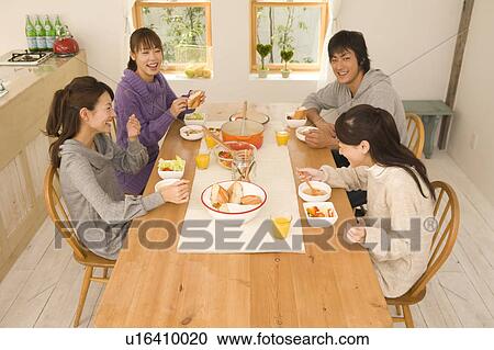 Stock Image - Young man and young women having home party. Fotosearch