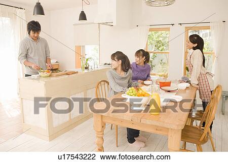 Stock Image - Young man cooking and young women waiting. Fotosearch