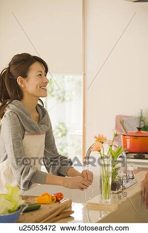 Stock Image - Young woman cooking in kitchen. Fotosearch