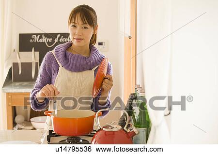 Stock Photograph - Young woman cooking in kitchen. Fotosearch