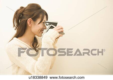 Young woman holding camera View Large Photo Image Stock Photo - Young woman holding camera. Fotosearch