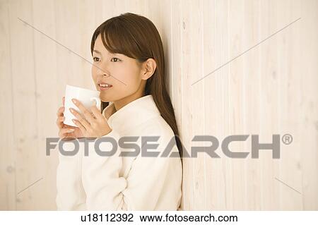 Stock Image - Young woman holding cup. Fotosearch