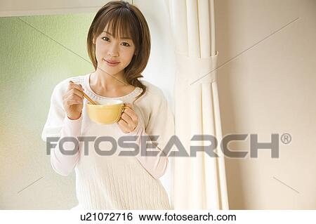Stock Photograph - Young woman holding cup. Fotosearch