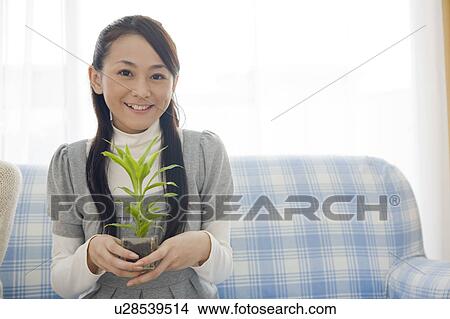 Picture - Young woman holding foliage plant pot. Fotosearch