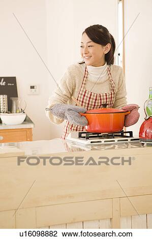 Stock Image - Young woman holding pot. Fotosearch