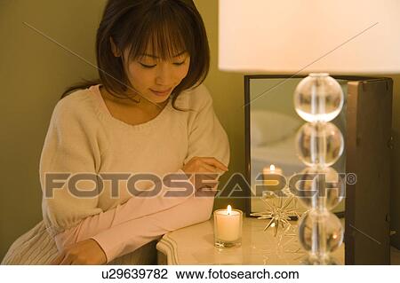 Stock Image - Young woman looking candle. Fotosearch