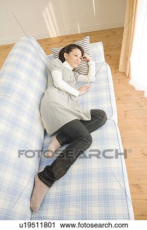Stock Image - Young woman lying on sofa. Fotosearch