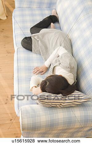 Stock Photo - Young woman lying on sofa. Fotosearch