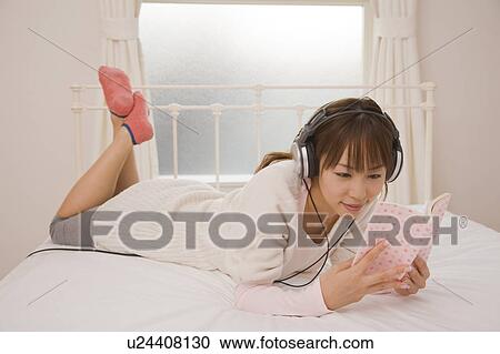 Young woman reading book on bed View Large Photo Image Stock Image - Young woman reading book on bed. Fotosearch