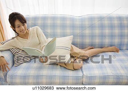 Young woman reading book on sofa View Large Photo Image Stock Image - Young woman reading book on sofa. Fotosearch