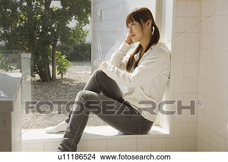 Picture - Young woman sitting near window. Fotosearch