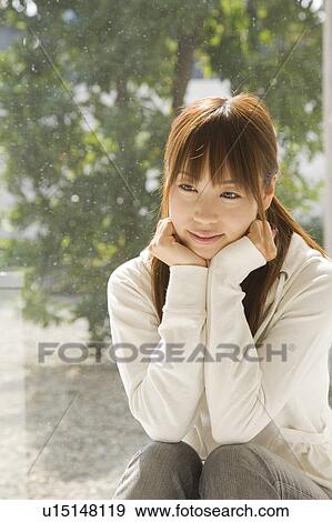 Young woman sitting near window View Large Photo Image Stock Photo - Young woman sitting near window. Fotosearch