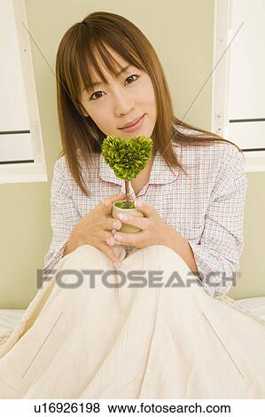 Young woman sitting on bed View Large Photo Image Stock Photo - Young woman sitting on bed. Fotosearch
