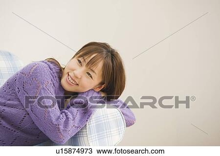 Stock Image - Young woman sitting on sofa. Fotosearch